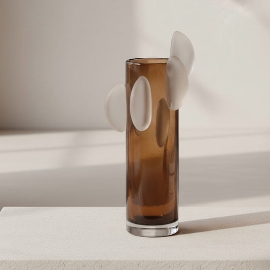 Eclectic amber brown glass vase with a tall cylindrical shape and sculptural white disc accents on a neutral surface.