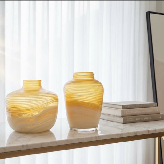 Eclectic amber marble effect glass vases with horizontal texture on a white marble console table.