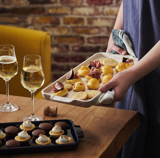 Eclectic Appolia ecru ceramic appetizer platter held by a person, featuring baked pastries on a wooden table.