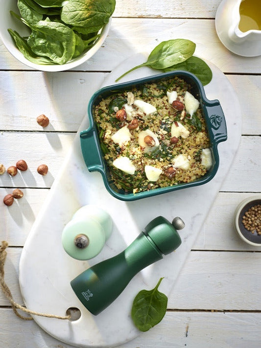 Eclectic Appolia forest green square ceramic oven dish filled with a quinoa and spinach bake on a white marble board.