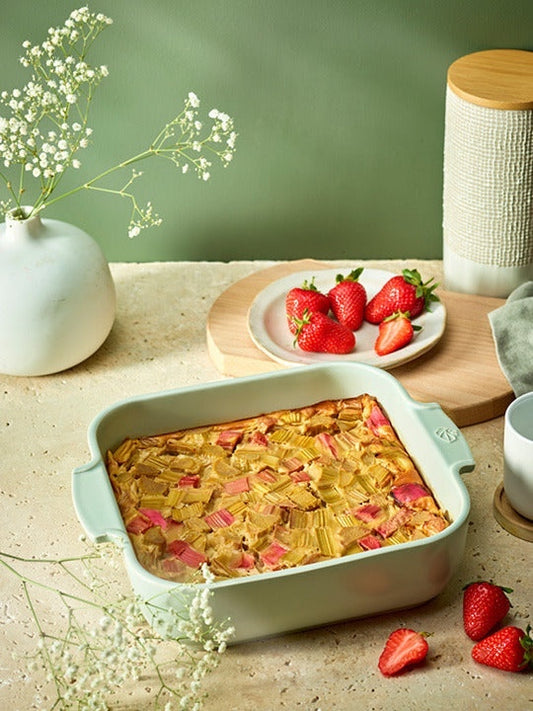 Eclectic Appolia square sage green ceramic oven dish filled with baked rhubarb dessert on a rustic kitchen table.