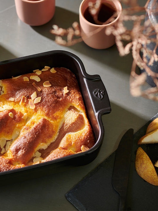 Eclectic Appolia rectangular ceramic oven dish in satin black filled with a baked pear dessert on a table.