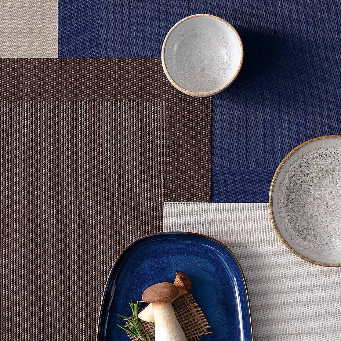 Eclectic ASA Selection brown PVC placemat with woven texture layered with blue and beige mats and ceramic bowls