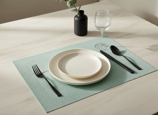 Eclectic ASA Selection jade PVC placemat with woven texture on a marble table with modern black cutlery and plates