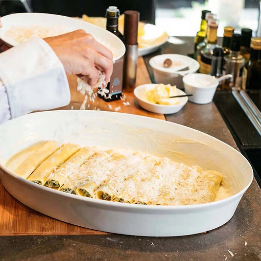 Eclectic ASA Selection white porcelain oval roasting dish being filled with cannelloni in a professional kitchen