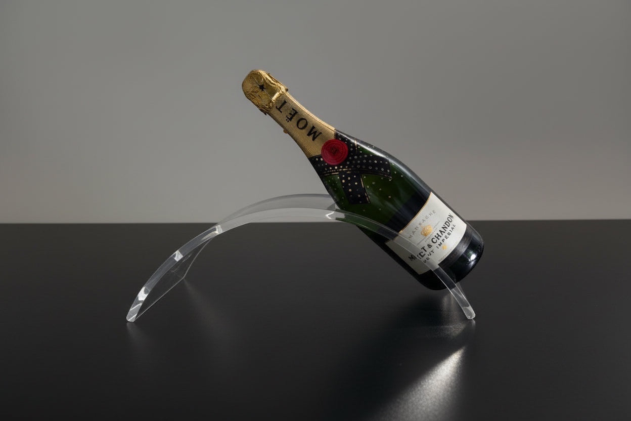 Eclectic clear acrylic wine holder with a curved design supporting a bottle of champagne on a black surface