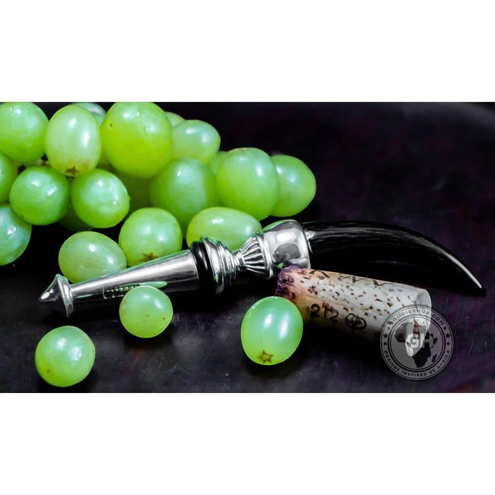 Eclectic Diana Carmichael Impondo Zulu bottle stopper with ebony resin horn handle and pewter detail beside green grapes