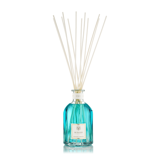 Eclectic Dr Vranjes Acqua reed diffuser in a blue glass bottle with natural sticks against a black background.