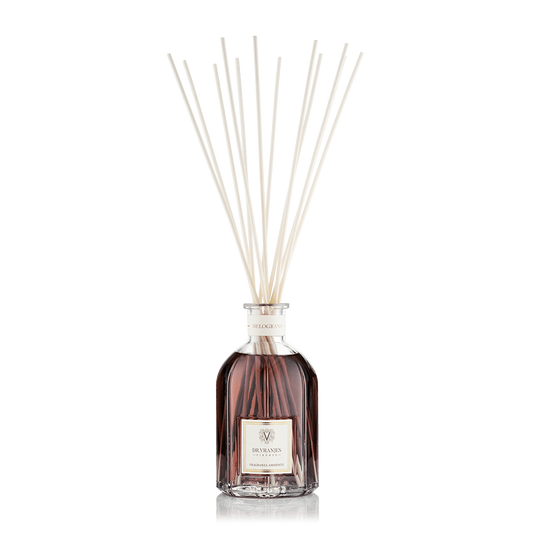 Eclectic Dr Vranjes Melograno reed diffuser in a glass bottle with natural sticks against a black background