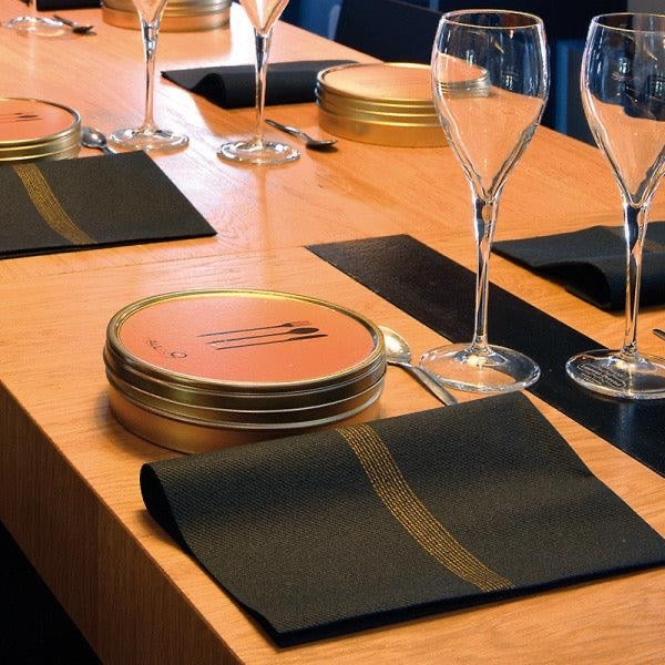 Eclectic Françoise Paviot Empreinte Or dinner napkins with gold lines on a dark background at a formal table setting
