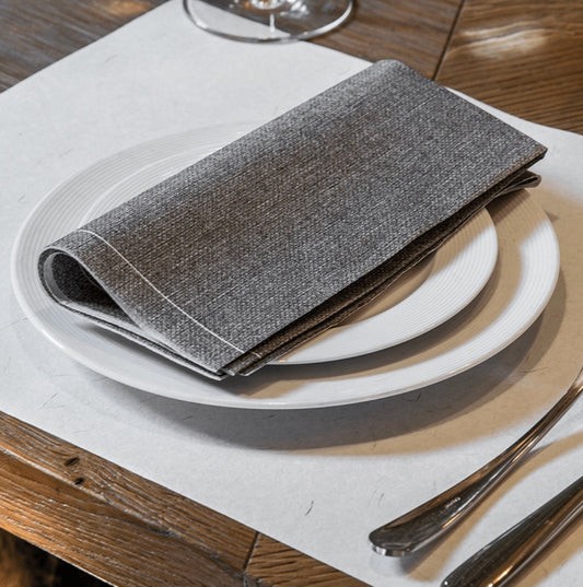 Eclectic Françoise Paviot Chine Gris grey airlaid dinner napkin folded on a white plate on a wooden table