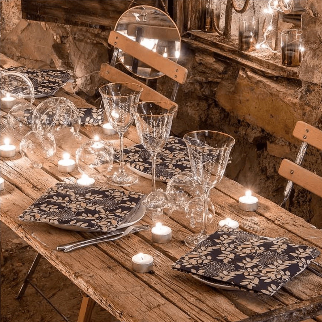 Eclectic Françoise Paviot Hibou Nuit dinner napkins with gold owl motif on a rustic wooden table setting.