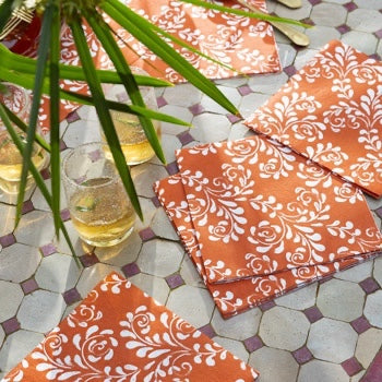 Eclectic Françoise Paviot Arabesque Terra dinner napkins with white floral patterns on a terracotta airlaid background.