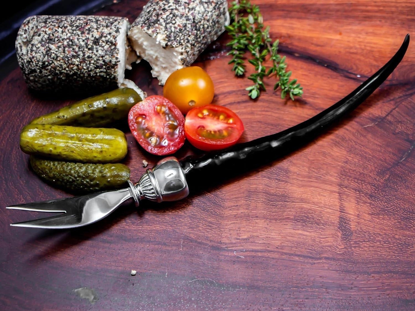 Eclectic Impondo Zulu pickle fork with black resin horn-style handle and stainless steel on a wooden serving board.