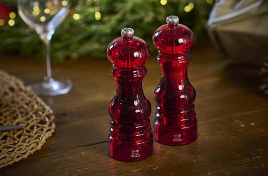 Eclectic Peugeot Podium red acrylic salt and pepper mill set on a wooden table with festive decor