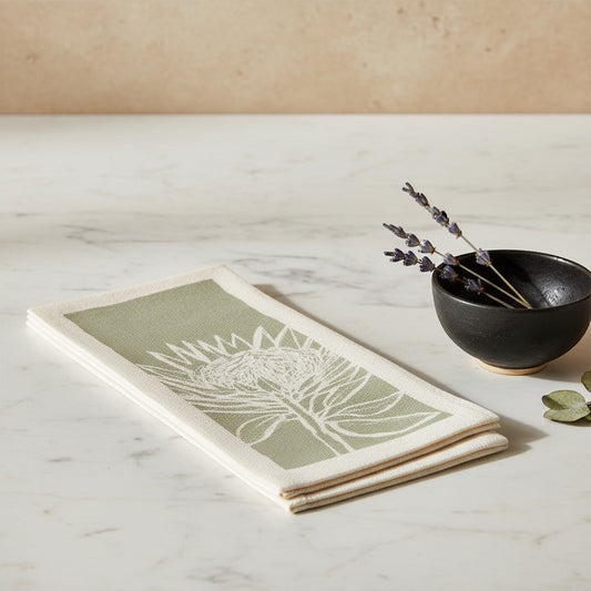 Eclectic Protea green botanical print airlaid disposable napkin with a linen-like texture on a marble surface.