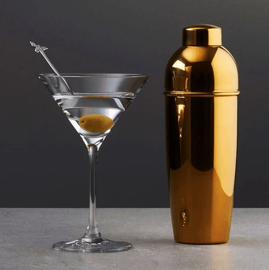 Eclectic Sambonet Sphera Parisienne cocktail shaker in cognac PVD stainless steel next to a martini glass with olive