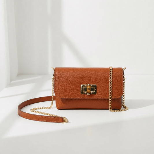 Eclectic tan pebbled leather clutch with a gold bamboo-style clasp and detachable gold chain strap.