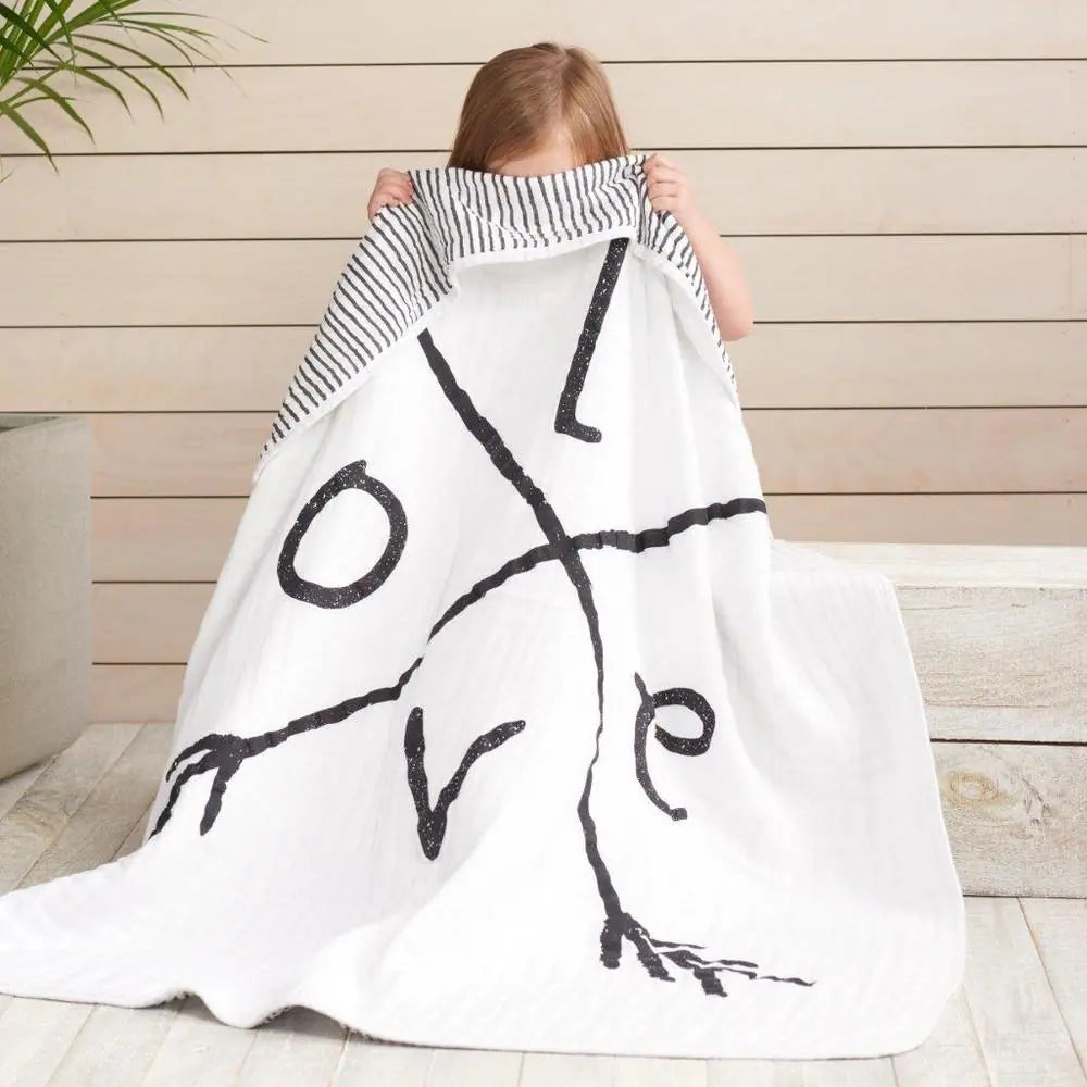 Aden & Anais baby linen collection with a soft patterned blanket.