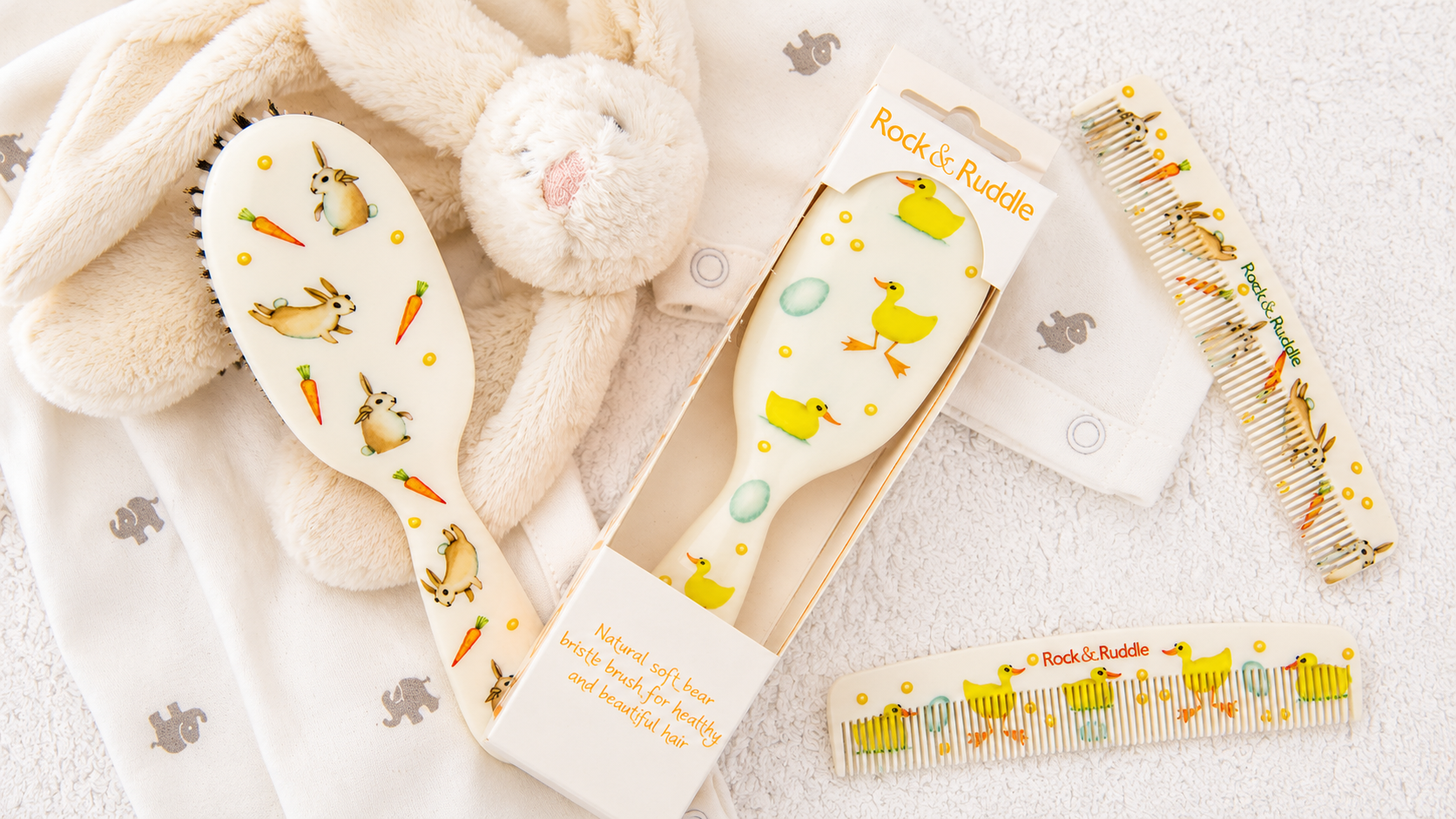 Baby brushes and combs with bunny and duck patterns displayed with soft baby accessories.
