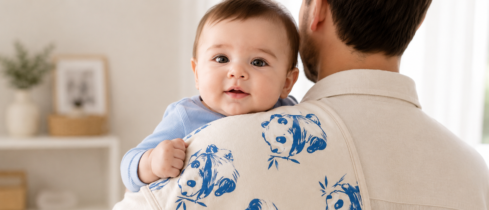 Baby resting on a parent’s shoulder with a patterned burp cloth.