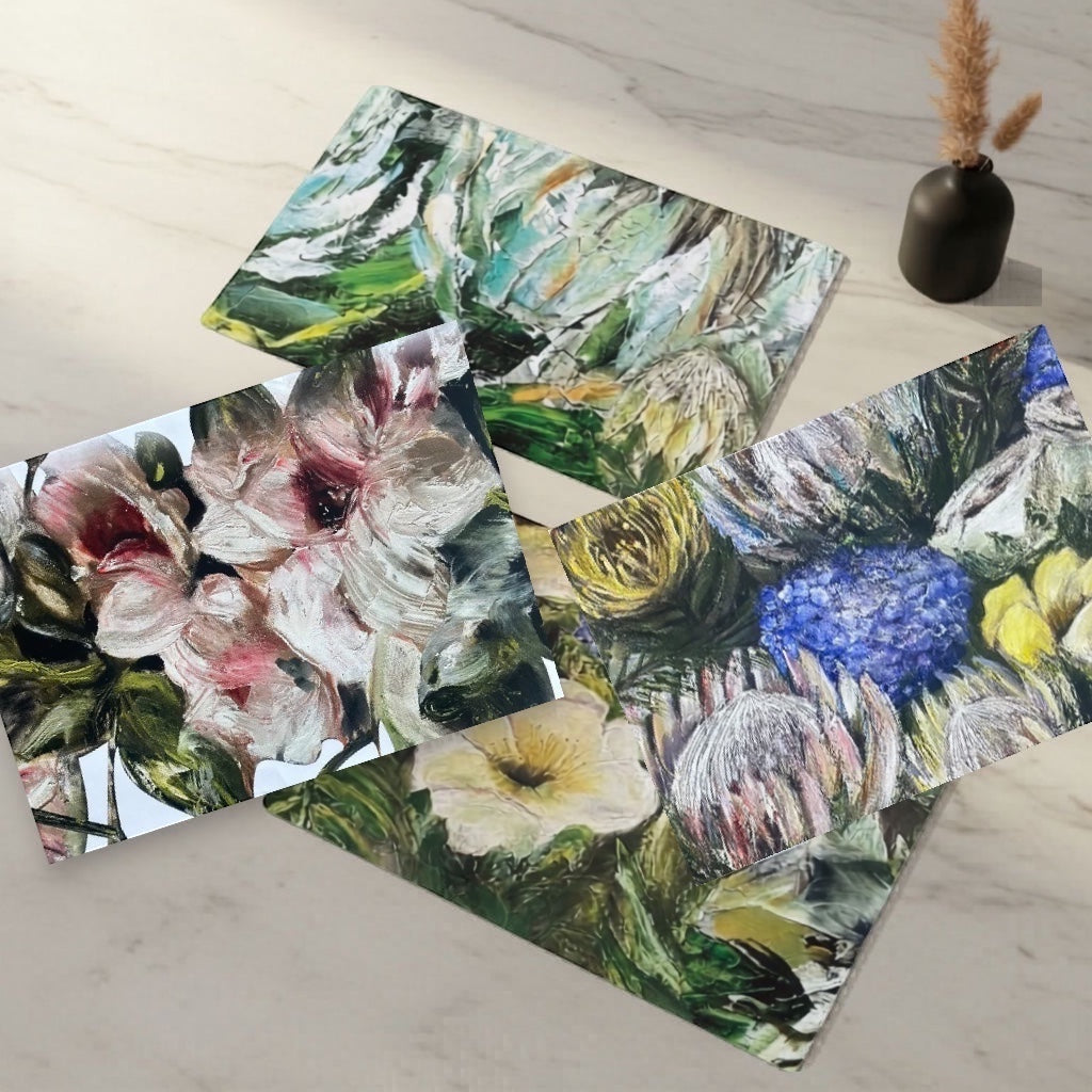 Eclectic abstract floral disposable paper placemats featuring painterly botanical designs on a marble table surface.