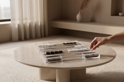 Eclectic modern acrylic backgammon set with black and white playing pieces on a beige stone coffee table.