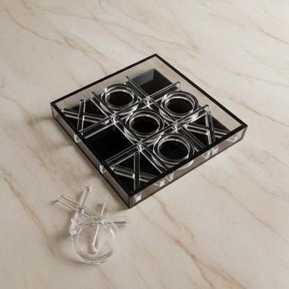 Eclectic modern acrylic noughts and crosses game with clear and black pieces on a marble surface