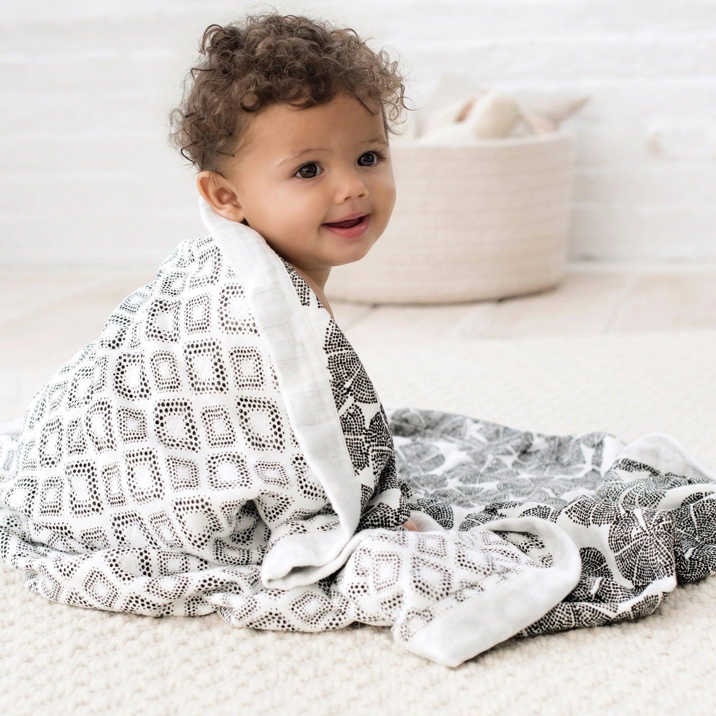 Eclectic Aden + Anais bamboo muslin dream blanket with black and white In Motion Wedges print wrapped around a baby
