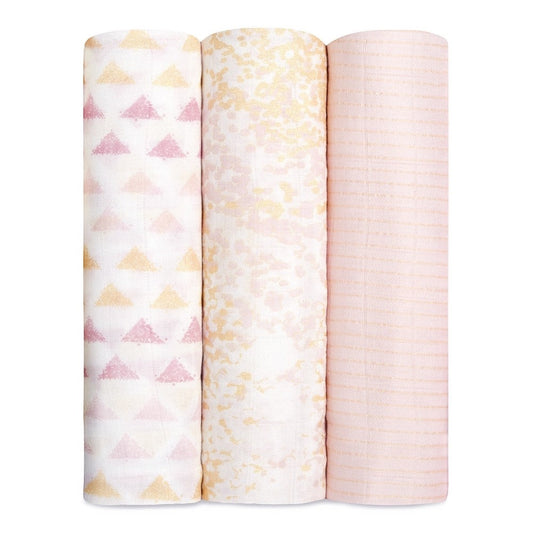 Eclectic Aden + Anais set of 3 metallic primrose birch bamboo muslin swaddles in soft pink and gold tones.