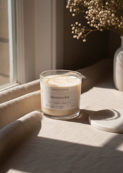 Eclectic Amanda Jayne honeysuckle soy candle in a glass tumbler with double wicks on a neutral linen surface