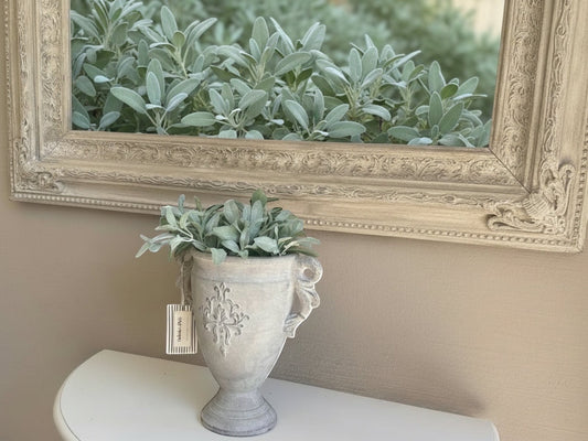 Eclectic antique cement trophy vase with ornate handles and weathered finish, styled on a console table.