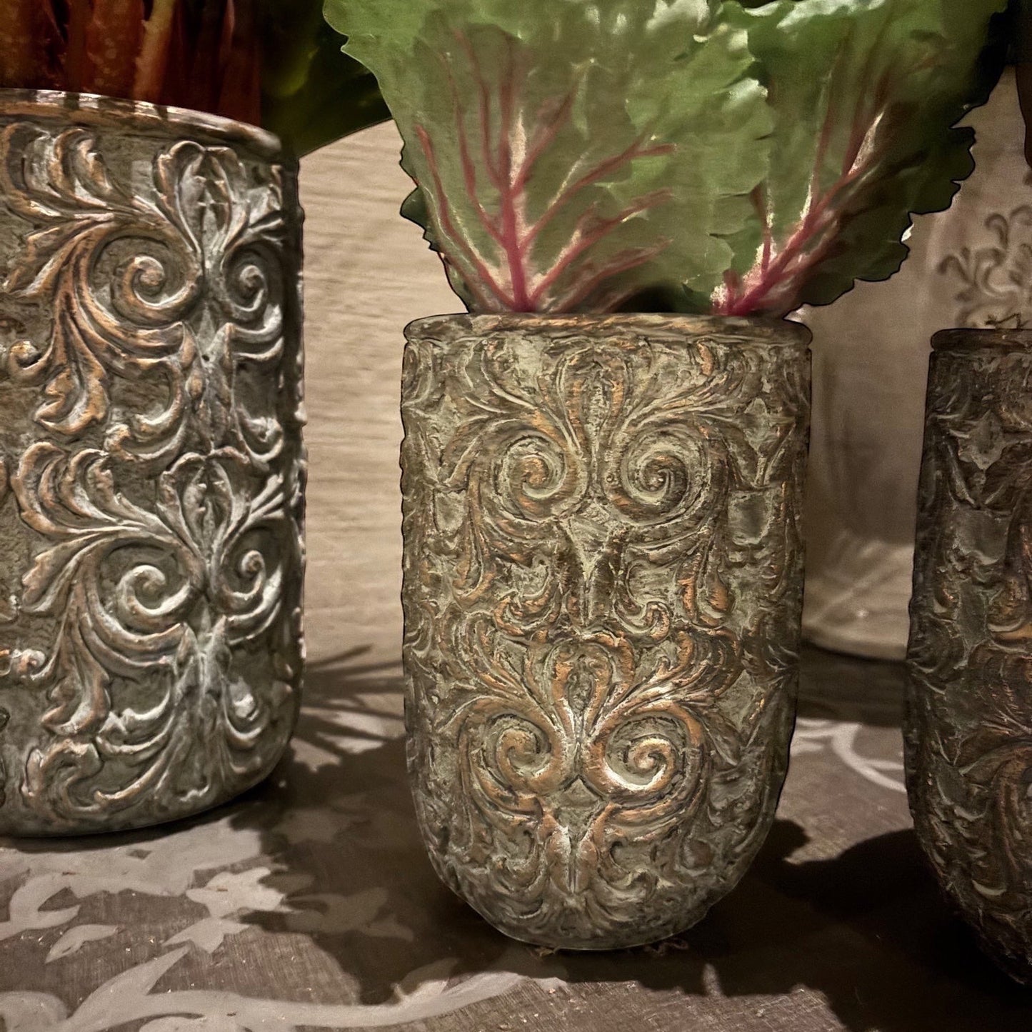 Eclectic antique scroll cement planter in aged green patina with bronze undertones and intricate relief detailing.