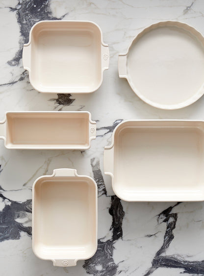 Eclectic Appolia ceramic oven dishes in ecru cream, featuring various shapes and sizes on a marble surface.
