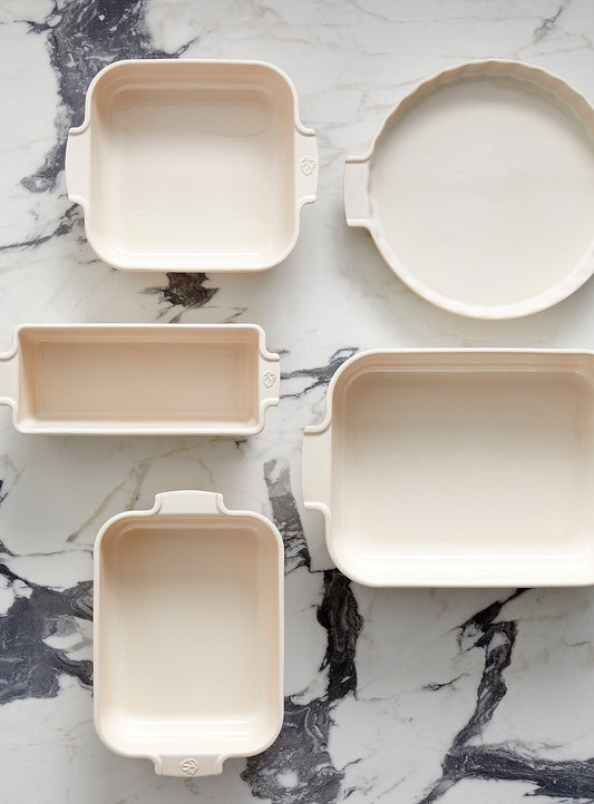 Eclectic Appolia collection of ecru ceramic oven dishes in various rectangular and round shapes on a marble surface