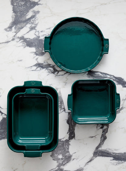 Eclectic Appolia forest green ceramic oven dishes in square and round shapes with ribbed handles on marble surface.