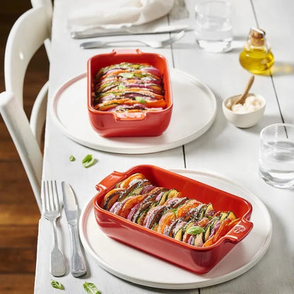 Eclectic Appolia rectangular ceramic oven dishes in rich red filled with roasted vegetables on a white dining table.