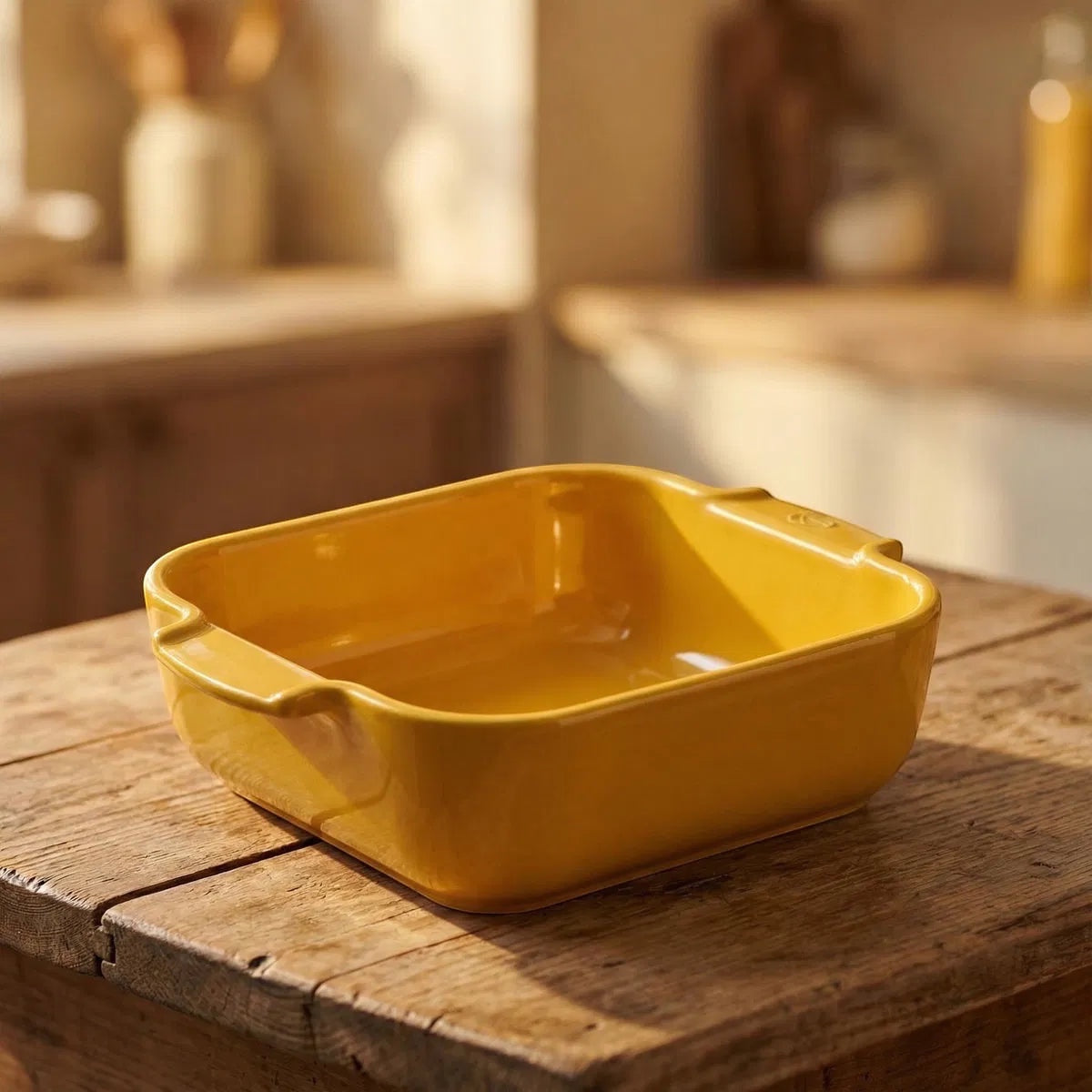 Eclectic Appolia square ceramic oven dish in saffron yellow with ribbed handles, sitting on a rustic wooden table.