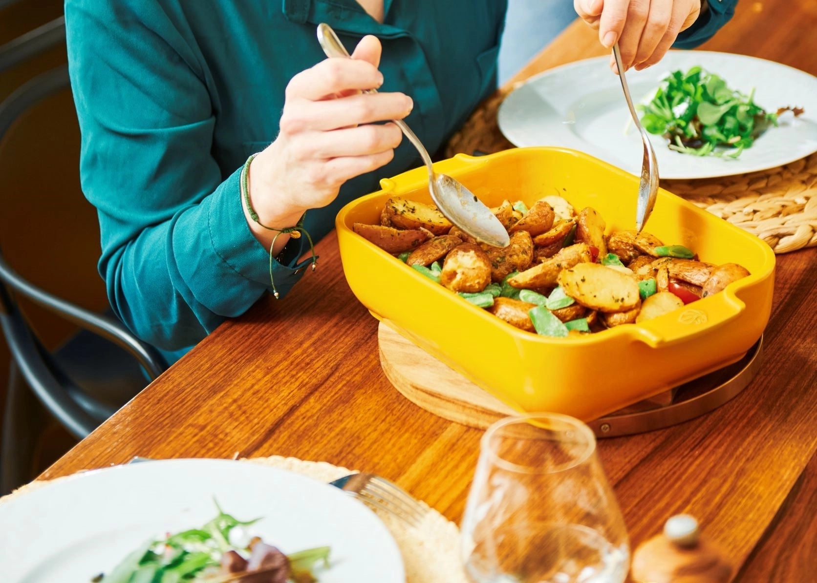 Eclectic Appolia saffron yellow ceramic rectangular oven dish filled with roasted potatoes on a wooden dining table