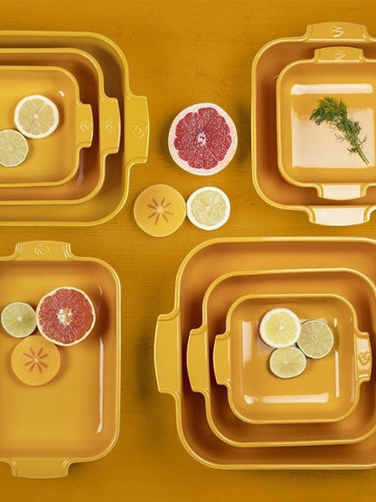 Eclectic Appolia saffron yellow ceramic square oven dishes in various sizes arranged on a matching yellow surface.