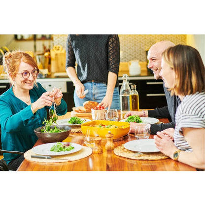 Friends enjoying a meal around a table with a bright saffron yellow Appolia rectangular ceramic oven dish