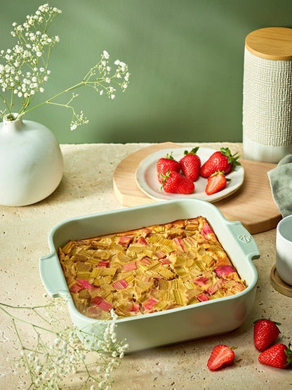 Eclectic Appolia square sage green ceramic oven dish filled with baked rhubarb dessert on a rustic kitchen table.