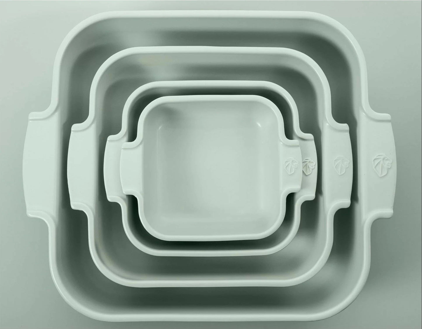 Eclectic Appolia sage green ceramic square oven dishes nested together, featuring ribbed handles and durable glaze.