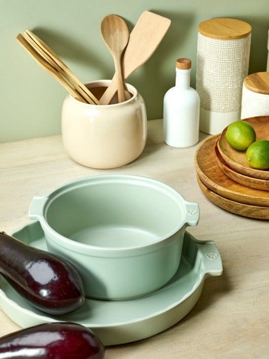 Eclectic Appolia sage green ceramic soufflé dish with ergonomic handles on a kitchen counter with fresh produce