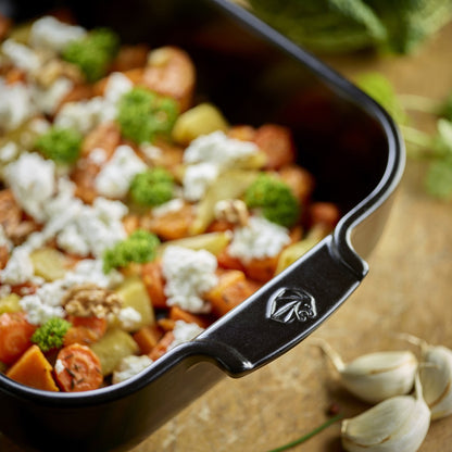 Eclectic Appolia satin black ceramic square oven dish filled with roasted vegetables, feta, and walnuts on a table.