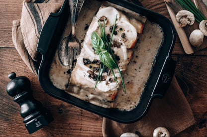 Eclectic Appolia square ceramic oven dish in satin black filled with creamy mushroom lasagna on a rustic wooden table