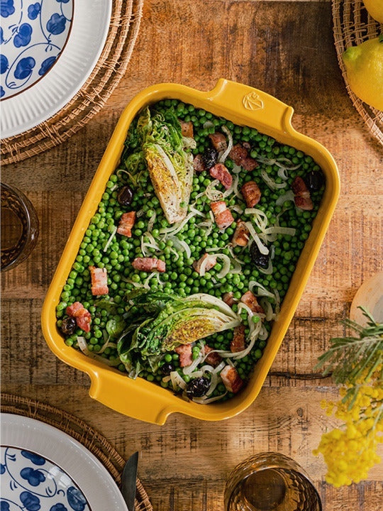 Eclectic Appolia saffron yellow ceramic rectangular oven dish filled with a pea, bacon, and lettuce salad on a table.
