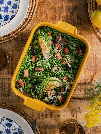 Eclectic Appolia saffron yellow ceramic rectangular oven dish filled with a pea, bacon, and lettuce salad on a table.