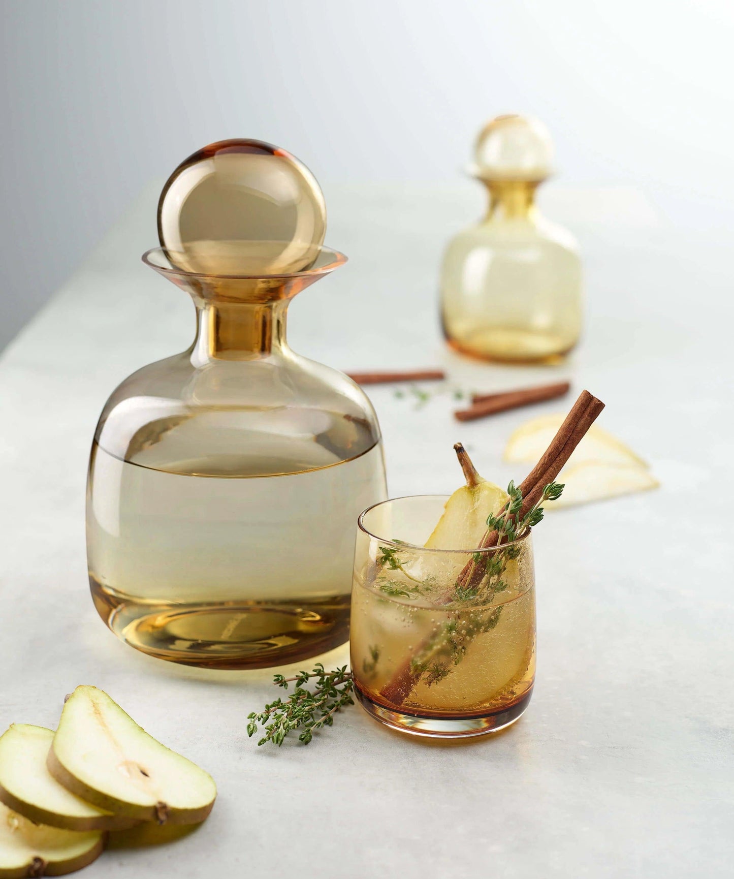 Eclectic ASA Selection Sarabi amber mouth-blown glass carafe with spherical stopper and matching glass on a table