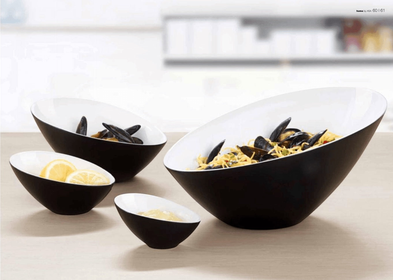 Eclectic ASA Selection Grande asymmetric bowls in black and white porcelain arranged on a table with food